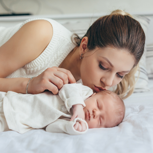 Mum and Baby laying on a bed while baby sleeps