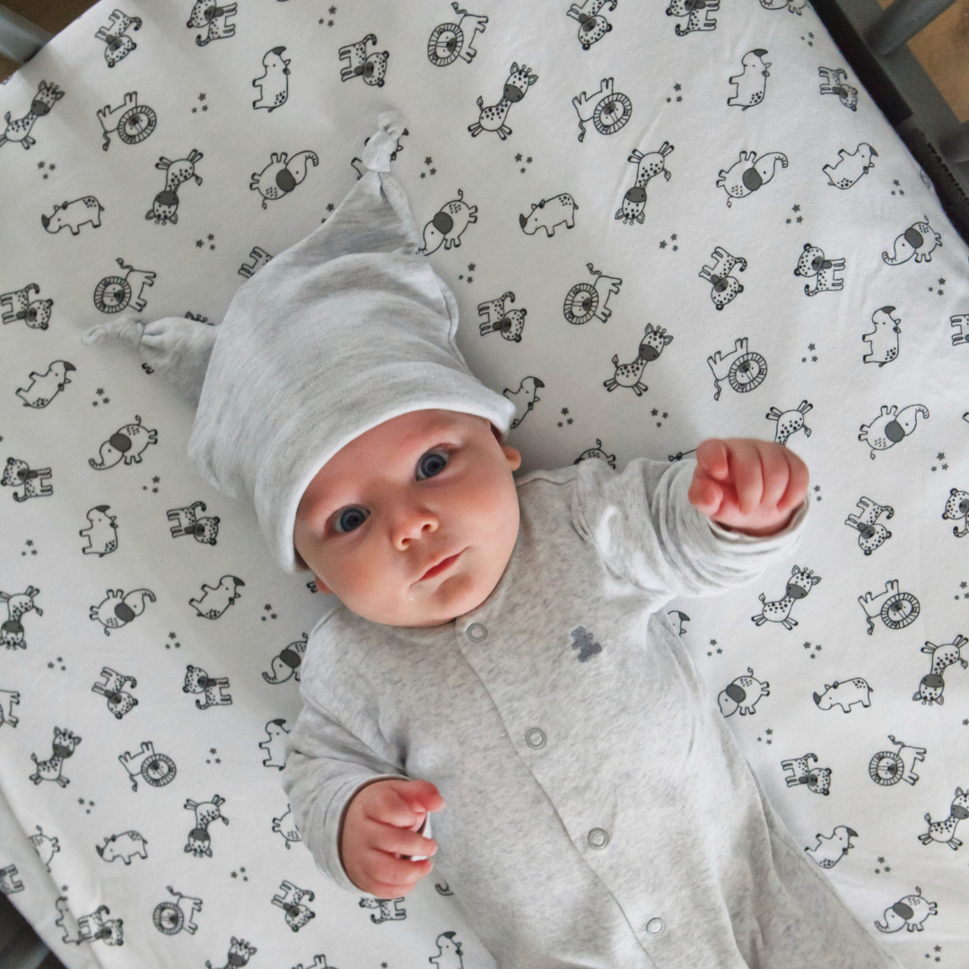 Baby lying on Safari Fitted Cot Sheet in a cot