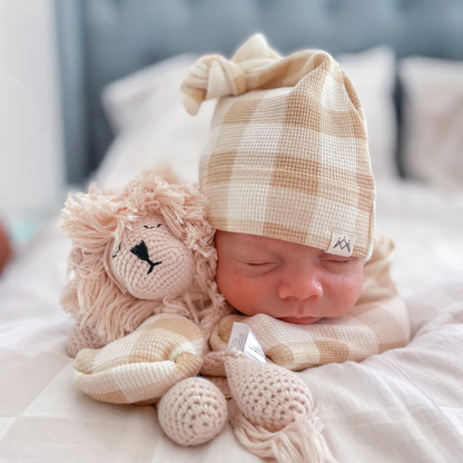 Gingham beanie on baby with lion comforter