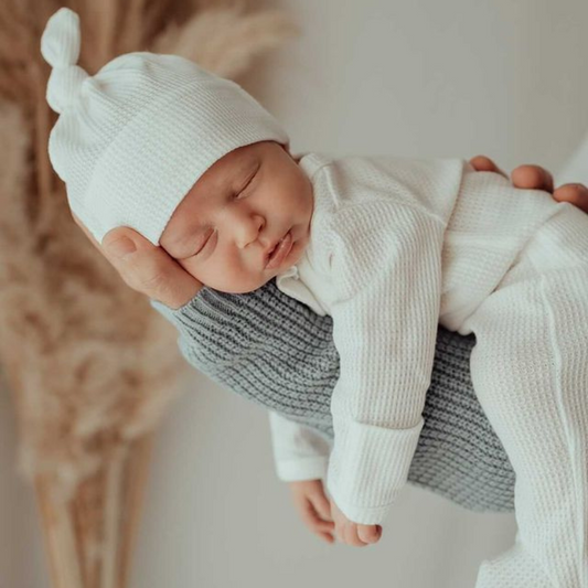 White My First Outfit and Beanie on Sleeping baby on dads arm