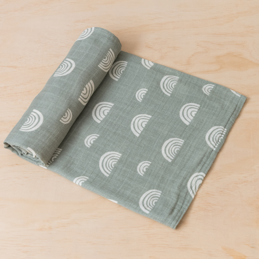 Kiin Baby Swaddle in Sage Rainbow rolled out on table