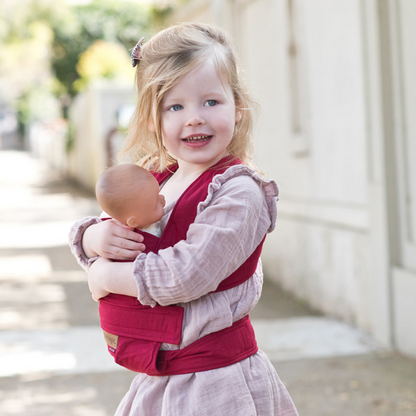Toddler wearing a baby carrier carrying her doll
