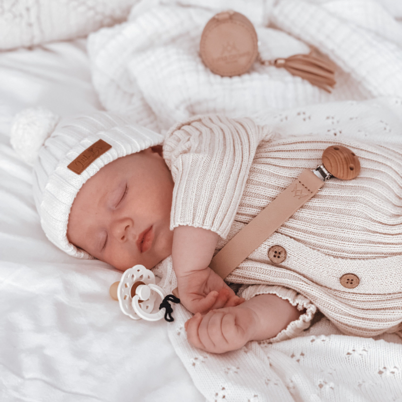 3 little crowns vegan leather dummy clip in nude and in use on sleeping baby attached to white dummy