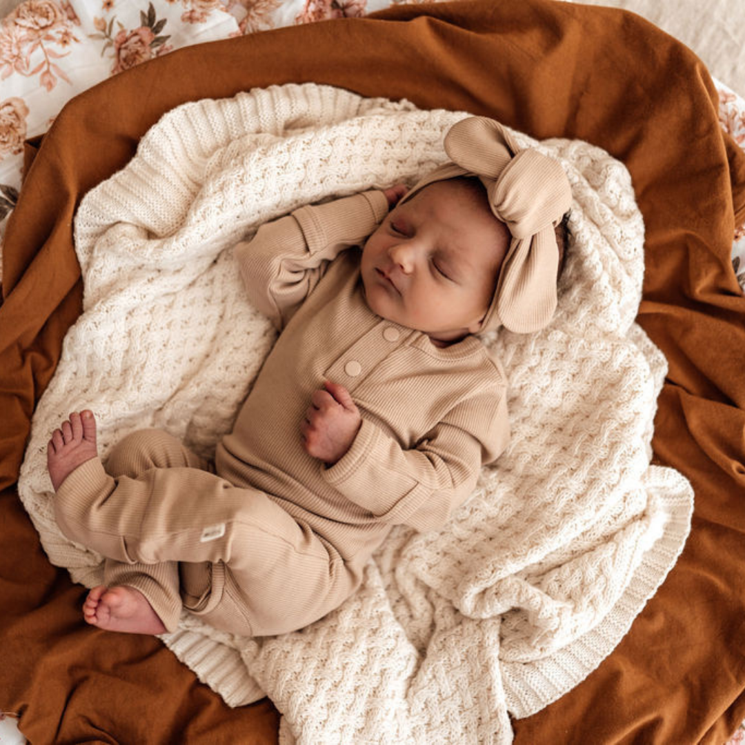 Snuggle Hunny Kids Growsuit Pebble on baby that is lying on a cream woollen blanket