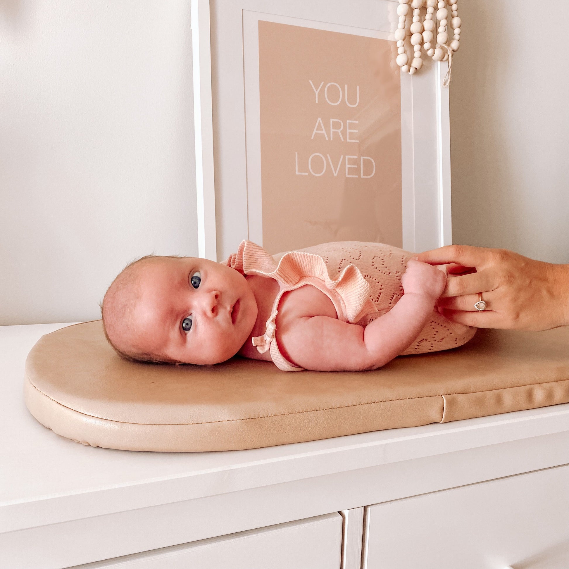 Newborn baby lying on nude colour vegan leather change pad